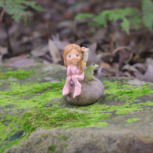 Cute little Fairy Child Sitting on a Rock with her little Frog Friend